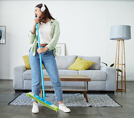 Image showing Woman, broom and singing with headphones for cleaning home, comic performance or music in living room. Girl cleaner, dancing and funny karaoke with energy, performance or streaming audio in lounge
