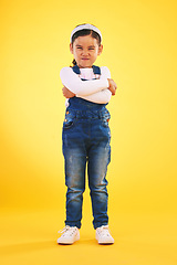 Image showing Arms crossed, angry and portrait of girl child in studio with bad, attitude or behavior problem on yellow background. Frown, face and asian kid with body language for no, frustrated or tantrum emoji