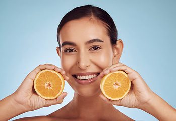 Image showing Happy woman, portrait and smile with orange vitamin C, skincare or diet against blue studio background. Female person with organic citrus fruit for natural nutrition, dermatology or healthy wellness
