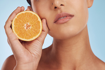 Image showing Woman, hands and orange for vitamin C, skincare or diet against a blue studio background. Closeup of female person holding organic citrus fruit for natural nutrition, dermatology or healthy wellness