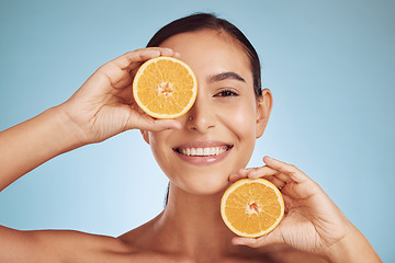 Image showing Happy woman, portrait and orange for natural vitamin C, skincare or diet against a blue studio background. Face of person smile with organic citrus fruit in nutrition, dermatology or healthy wellness