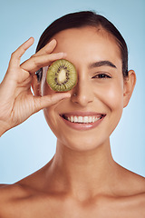 Image showing Skincare portrait, kiwi and woman with eye beauty, cosmetics and natural product, health and vitamin c. Face of young happy person or model, green fruits and dermatology on a studio, blue background