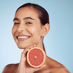 Image showing Happy woman, skincare portrait and grapefruit for beauty, cosmetics, natural product and tropical facial or vitamin c. Face of person or model with red fruit for dermatology on studio blue background