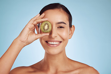 Image showing Beauty portrait, kiwi and woman with eye skincare, cosmetics and natural product, health and vitamin c. Face of young happy person or model, green fruits and dermatology on a studio, blue background