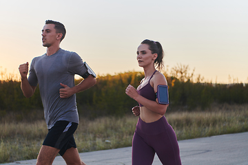 Image showing A handsome young couple running together during the early morning hours, with the mesmerizing sunrise casting a warm glow, symbolizing their shared love and vitality