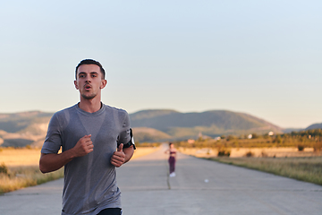 Image showing A handsome young couple running together during the early morning hours, with the mesmerizing sunrise casting a warm glow, symbolizing their shared love and vitality