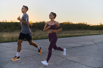 Image showing A handsome young couple running together during the early morning hours, with the mesmerizing sunrise casting a warm glow, symbolizing their shared love and vitality