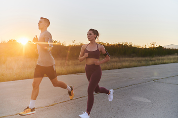 Image showing A handsome young couple running together during the early morning hours, with the mesmerizing sunrise casting a warm glow, symbolizing their shared love and vitality