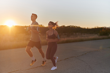 Image showing A handsome young couple running together during the early morning hours, with the mesmerizing sunrise casting a warm glow, symbolizing their shared love and vitality