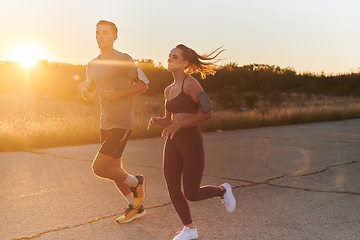 Image showing A handsome young couple running together during the early morning hours, with the mesmerizing sunrise casting a warm glow, symbolizing their shared love and vitality