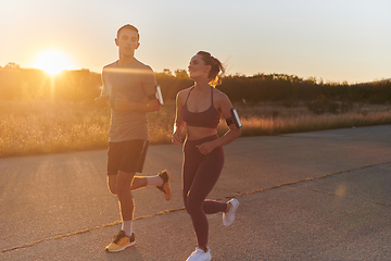 Image showing A handsome young couple running together during the early morning hours, with the mesmerizing sunrise casting a warm glow, symbolizing their shared love and vitality