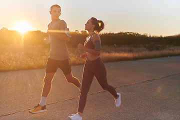 Image showing A handsome young couple running together during the early morning hours, with the mesmerizing sunrise casting a warm glow, symbolizing their shared love and vitality