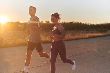 Image showing A handsome young couple running together during the early morning hours, with the mesmerizing sunrise casting a warm glow, symbolizing their shared love and vitality