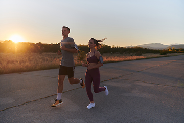 Image showing A handsome young couple running together during the early morning hours, with the mesmerizing sunrise casting a warm glow, symbolizing their shared love and vitality