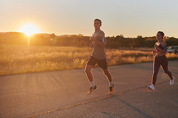 Image showing A handsome young couple running together during the early morning hours, with the mesmerizing sunrise casting a warm glow, symbolizing their shared love and vitality