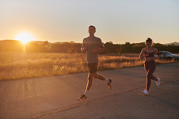 Image showing A handsome young couple running together during the early morning hours, with the mesmerizing sunrise casting a warm glow, symbolizing their shared love and vitality