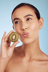 Image showing Woman, thinking and kiwi for natural nutrition, diet or skincare against a blue studio background. Female person or model with organic fruit for healthy wellness, beauty or facial spa treatment