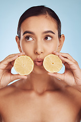 Image showing Woman, hands and lemon for skincare detox, diet or collagen against a blue studio background. Female person or model holding organic citrus fruit for natural nutrition, anti aging or facial treatment