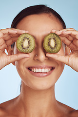 Image showing Fruit, eyes and woman with kiwi for beauty or organic dermatology treatment isolated in a blue studio background. Skin, skincare and young female person with facial wellness, nutrition and detox