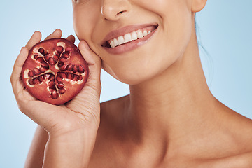 Image showing Smile, skincare and hands of woman with pomegranate in studio isolated on a blue background. Natural, fruit and face of model with food for nutrition, healthy vegan diet and vitamin c for wellness.