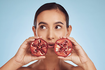 Image showing Face, skincare and woman with pomegranate for beauty in studio isolated on a blue background. Natural cosmetic, fruit and model with food for nutrition, healthy vegan diet and vitamin c for wellness.