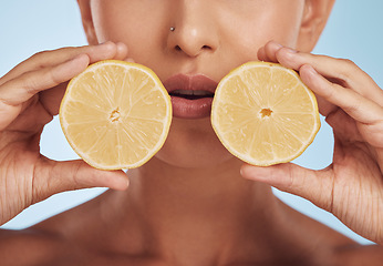 Image showing Woman, hands and lemon for natural skincare, diet or detox against a blue studio background. Closeup of female person with organic citrus fruit slices for healthy wellness, collagen or vitamin C