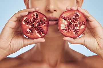 Image showing Hands, skincare and woman with pomegranate for beauty in studio isolated on a blue background. Natural, fruit and face of model with food for nutrition, healthy vegan diet and vitamin c for wellness