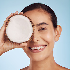 Image showing Young woman, coconut fruit and eye beauty, skincare or vegan cream on studio, blue background. Happy person or model with natural product for dermatology, eco friendly cosmetics and oil benefits