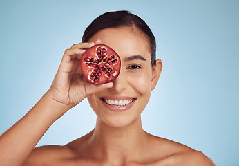 Image showing Woman, beauty portrait and pomegranate for skincare, cosmetics and natural facial product or vitamin c benefits. Face of person or model with red fruits for eye dermatology on studio blue background