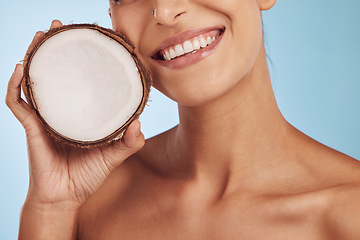 Image showing Happy woman, hands and coconut for skincare, diet or natural nutrition against a blue studio background. Closeup of female person smile with organic fruit for healthy wellness or facial spa treatment