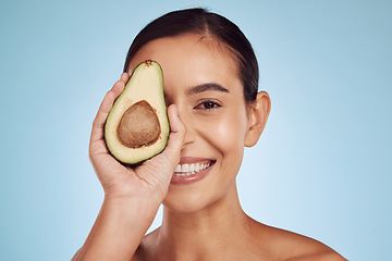 Image showing Avocado, eye skincare and woman in portrait for healthy face or natural cosmetics on studio blue background. Happy person or model of green fruits, vitamin d benefits and dermatology or beauty health