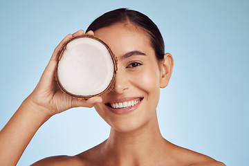 Image showing Happy woman, coconut fruit and eye beauty, skincare or vegan cream on studio, blue background. Young model or person with natural product for dermatology, eco friendly cosmetics and oil benefits