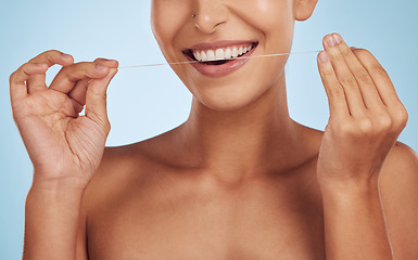 Image showing Teeth whitening, flossing and woman, dental and hands, hygiene and grooming with oral care isolated on blue background. Closeup of female model cleaning mouth, health and morning routine in studio