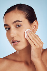 Image showing Woman, face and cotton pad for skincare or makeup removal against a blue studio background. Portrait of female person with swab for cleaning foundation, beauty cosmetics or facial skin treatment