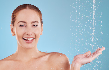 Image showing Portrait, hand and water splash with girl for skincare in studio or blue background with face. Woman, shower and sustainability with drop for beauty routine with cosmetics or dermatology with smile.