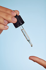 Image showing Skincare oil, beauty and hands on a blue background for wellness, cosmetics and luxury. Closeup, health and a person with a serum dropper for beauty and product isolated on a studio backdrop