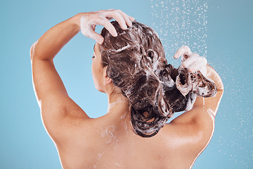 Image showing Woman, back and shampoo, haircare in shower and hygiene with water drops on blue background. Grooming, cosmetic care and sustainability, female person and morning routine, soap or foam in hair