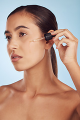 Image showing Face, skincare and serious woman with serum for beauty in studio isolated on a blue background. Cosmetics, model and essential oil, collagen and hyaluronic acid for dermatology, health and wellness.