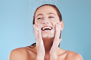Image showing Woman, cleaning face and soap with beauty, shower and hygiene with grooming isolated on blue background. Female model, sustainability and water drop with happiness, dermatology and skincare in studio