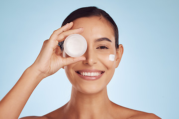Image showing Woman, face and cream container for eye skincare, dermatology and cosmetics or collagen. Facial product, happy portrait of young person or beauty model with skin care lotion on studio blue background