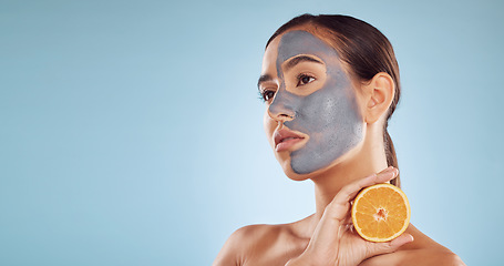 Image showing Mockup, orange and mask for beauty with a woman in studio on a blue background for antiaging skincare. Face, facial and thinking with an attractive young person holding fruit for natural treatment