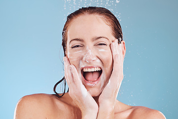 Image showing Shower, skincare and smile with portrait of woman in studio for beauty, hygiene and soap. Facial, water and splash with face of person on blue background for cosmetics, spa treatment and soap