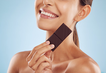 Image showing Smile, skincare and woman with chocolate for beauty isolated on a blue background. Happy, candy and model with food, cacao and dessert, sweets and sugar for eating, cholesterol and natural cosmetics