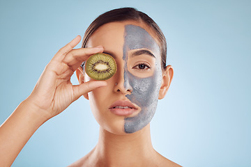 Image showing Portrait, kiwi and mask for beauty with a woman in studio on a blue background for antiaging skincare. Face, facial and fruit with an attractive young female holding a berry for natural treatment