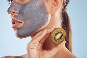 Image showing Fruit, face mask and woman with kiwi for charcoal skincare or organic treatment isolated in a blue studio background. Skin, beauty and young female person with facial wellness, nutrition and detox