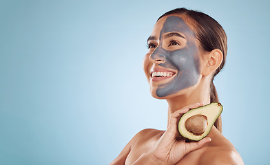 Image showing Mockup, avocado and mask for beauty with a woman in studio on a blue background for antiaging skincare. Facial, smile and idea with an attractive young person holding a fruit for detox or treatment