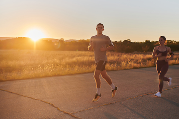 Image showing A handsome young couple running together during the early morning hours, with the mesmerizing sunrise casting a warm glow, symbolizing their shared love and vitality