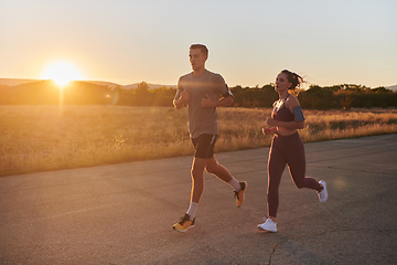 Image showing A handsome young couple running together during the early morning hours, with the mesmerizing sunrise casting a warm glow, symbolizing their shared love and vitality