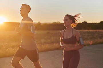 Image showing A handsome young couple running together during the early morning hours, with the mesmerizing sunrise casting a warm glow, symbolizing their shared love and vitality