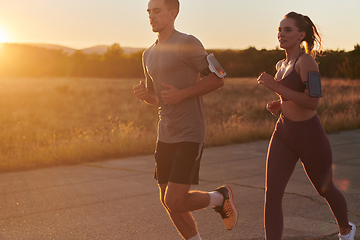 Image showing A handsome young couple running together during the early morning hours, with the mesmerizing sunrise casting a warm glow, symbolizing their shared love and vitality